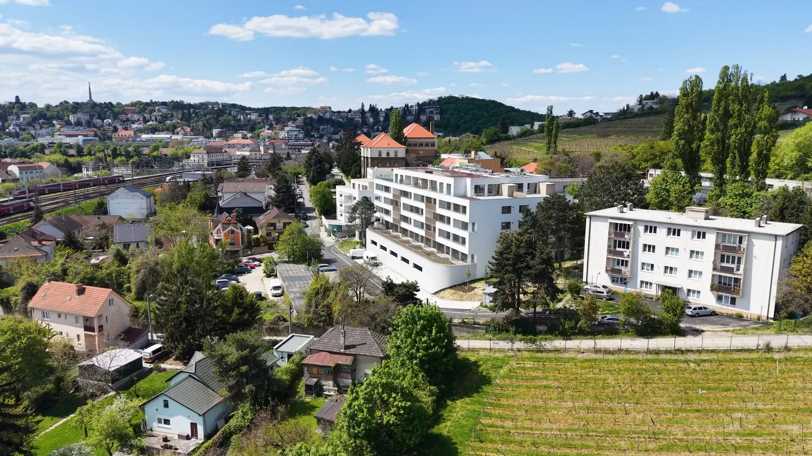 Bytový dom Winehills medzi rodinnými domami a vinicami pod Kolibou, v pozadí Bratislava